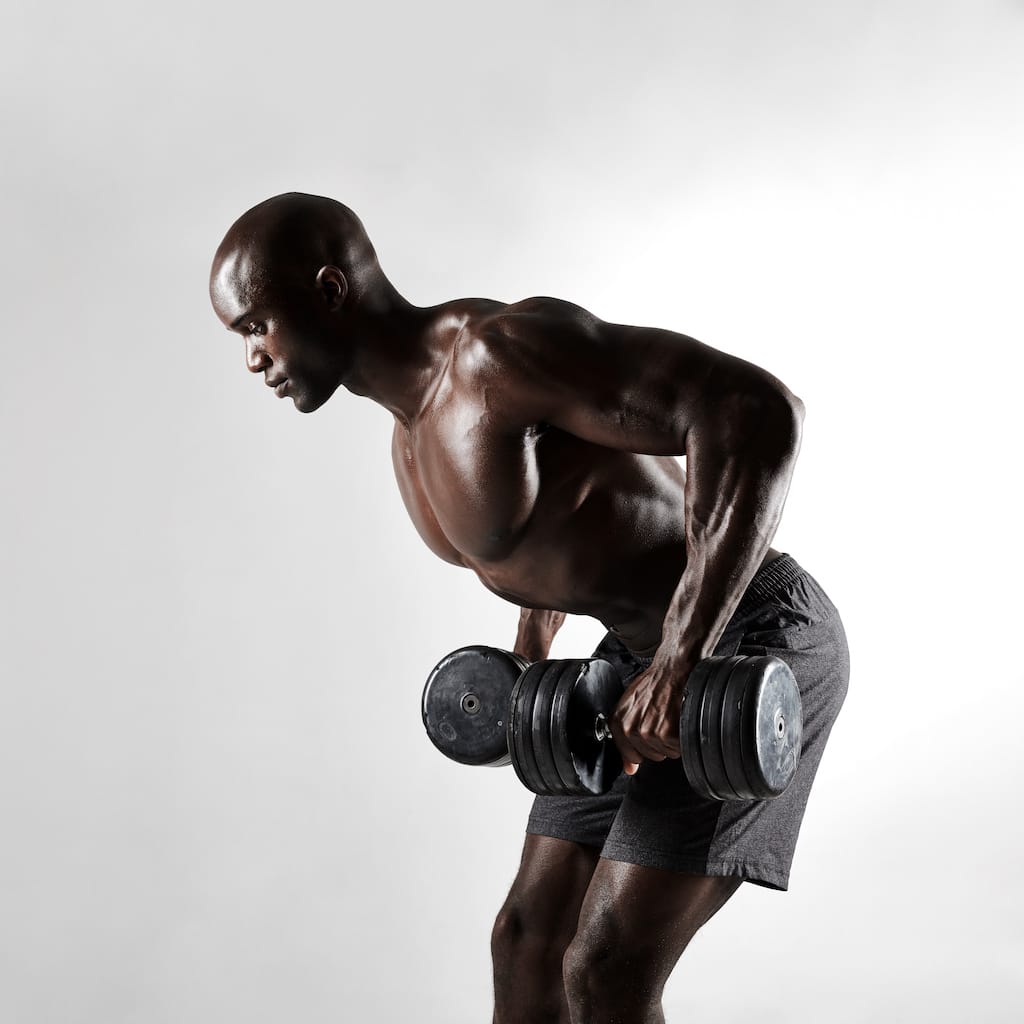 Bodybuilder mid-set on dumbbell work.